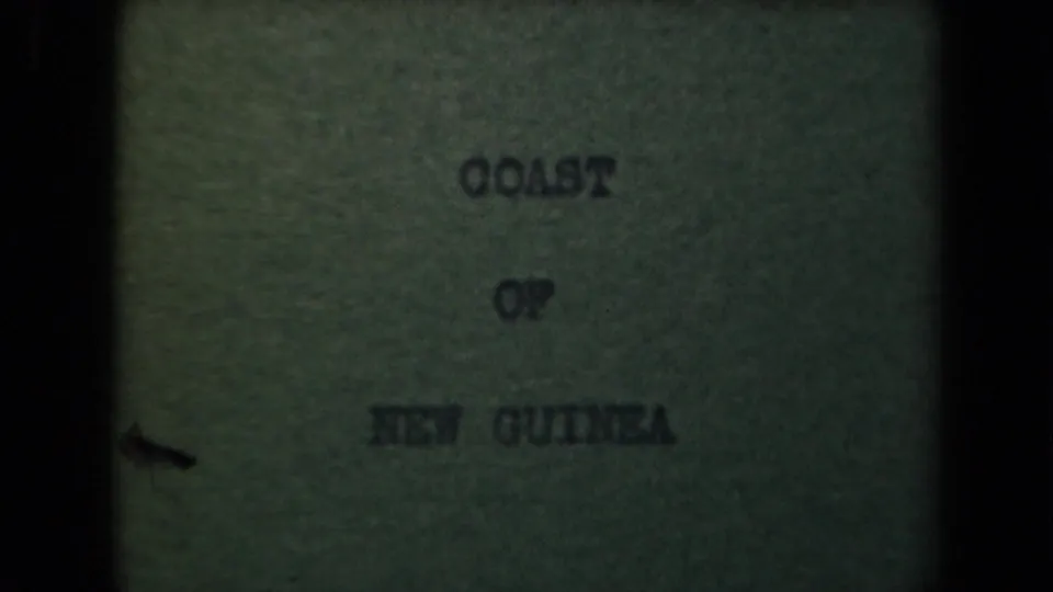 Centered Coast of New Guinea intertitle from a 1944 8mm home movie, framed by dark borders and visible film texture.