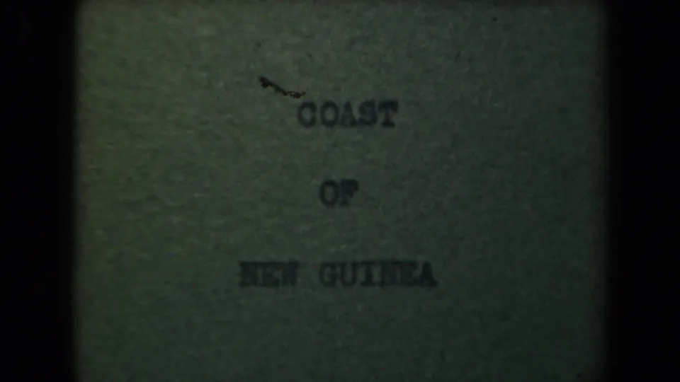 Aged 8mm title card for the coast of New Guinea, tinted green with soft focus and heavy frame shadows.