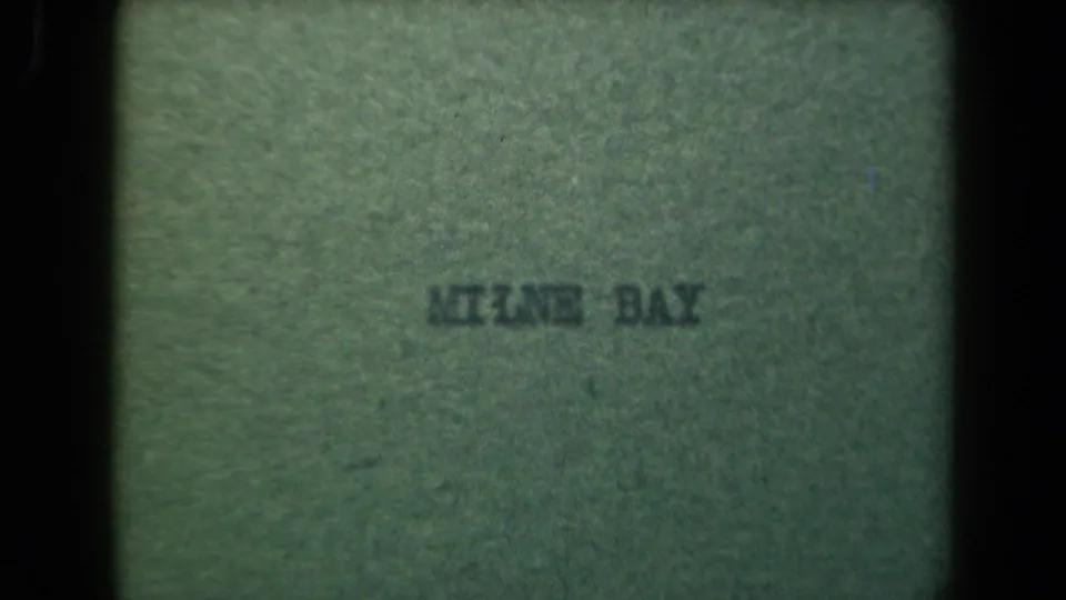 Milne Bay title card in faded green tones, with soft printed lettering and visible film texture.