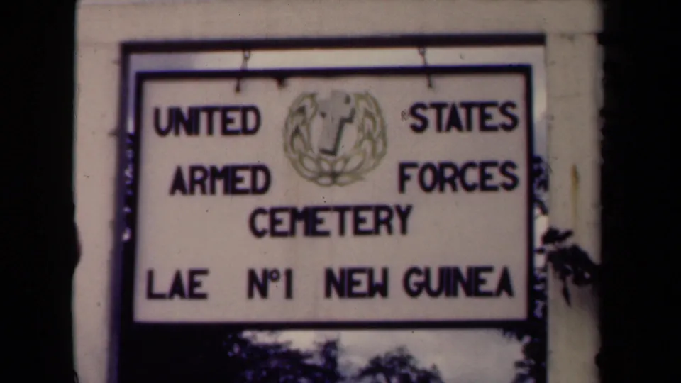 A slightly shifted frame shows the Lae No. 1 New Guinea cemetery sign in soft 8mm focus.