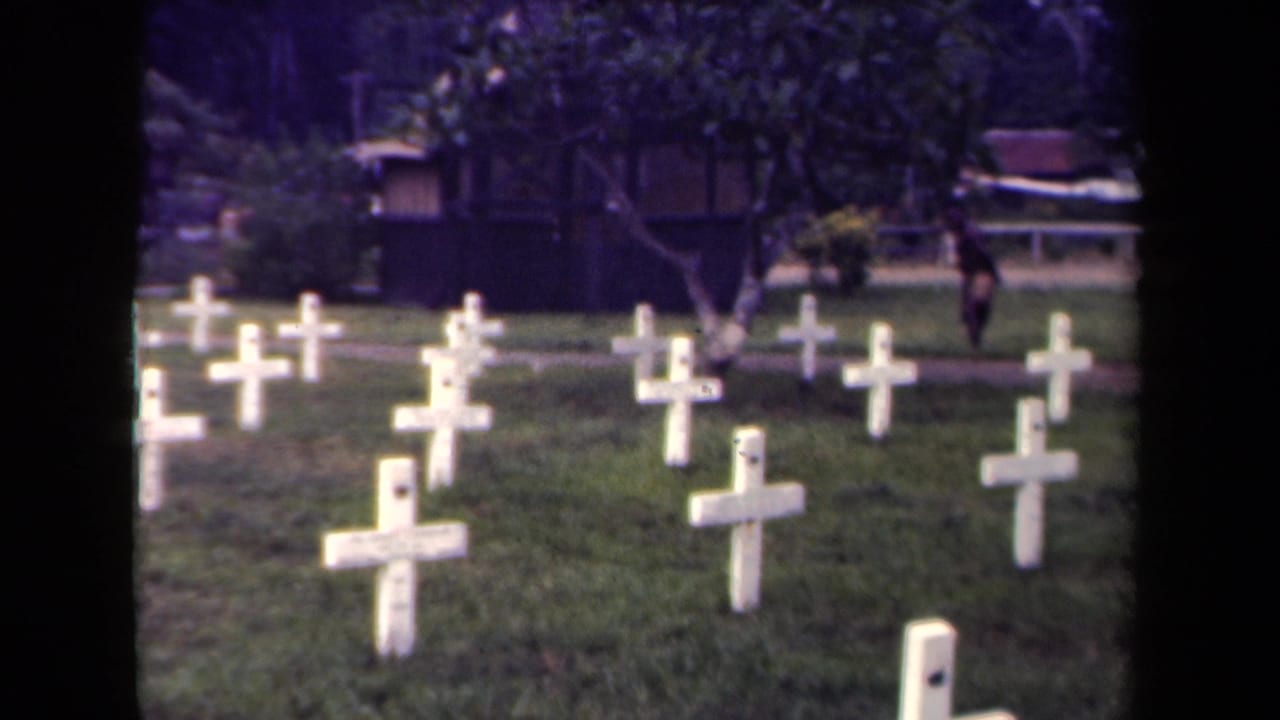 1940s Papua New Guinea cemetery view with rows of white crosses and a distant person walking near the background path.