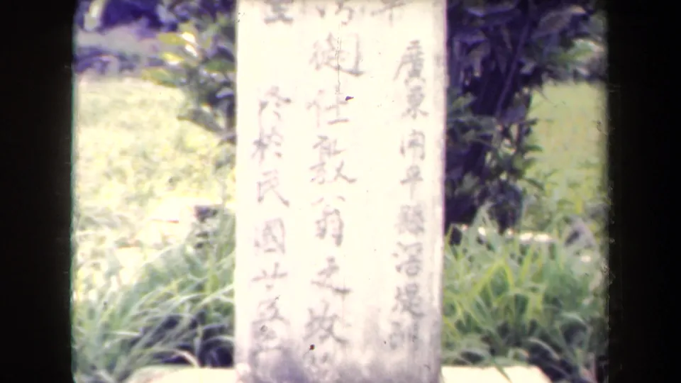 Close 8mm view of a pale memorial stone with vertical Chinese inscription in Papua New Guinea.