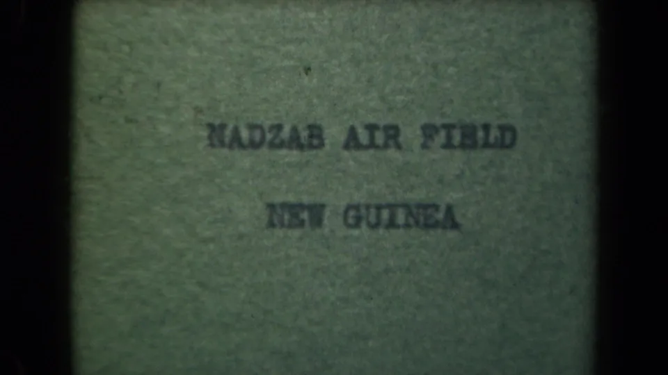 1944 New Guinea reel title card with typewritten Nadzab Air Field wording, dim exposure, and small-gauge film texture.