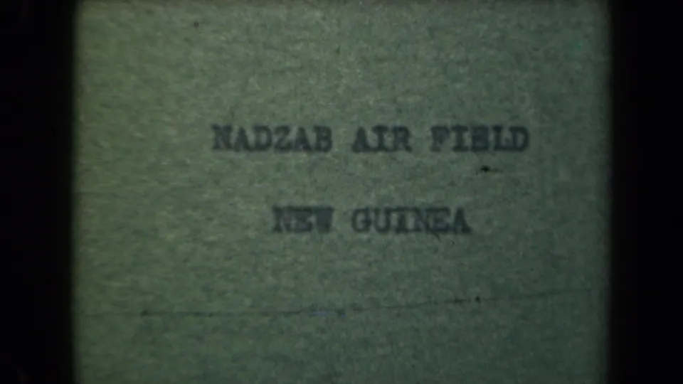 Final 1944 8mm frame of the Nadzab Air Field, New Guinea title card, with grain, soft lettering, and border shadows.