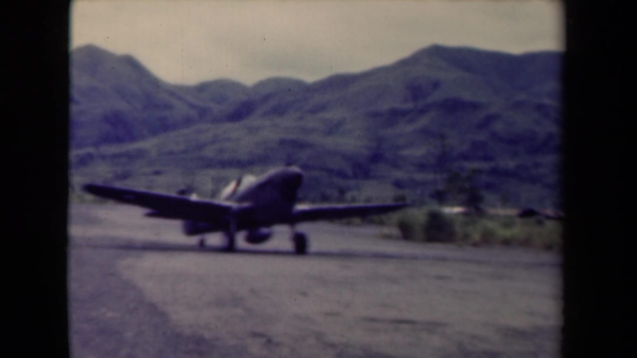 1944 Papua New Guinea footage shows a military propeller aircraft on a mountain airfield runway, framed through soft 8mm film edges.