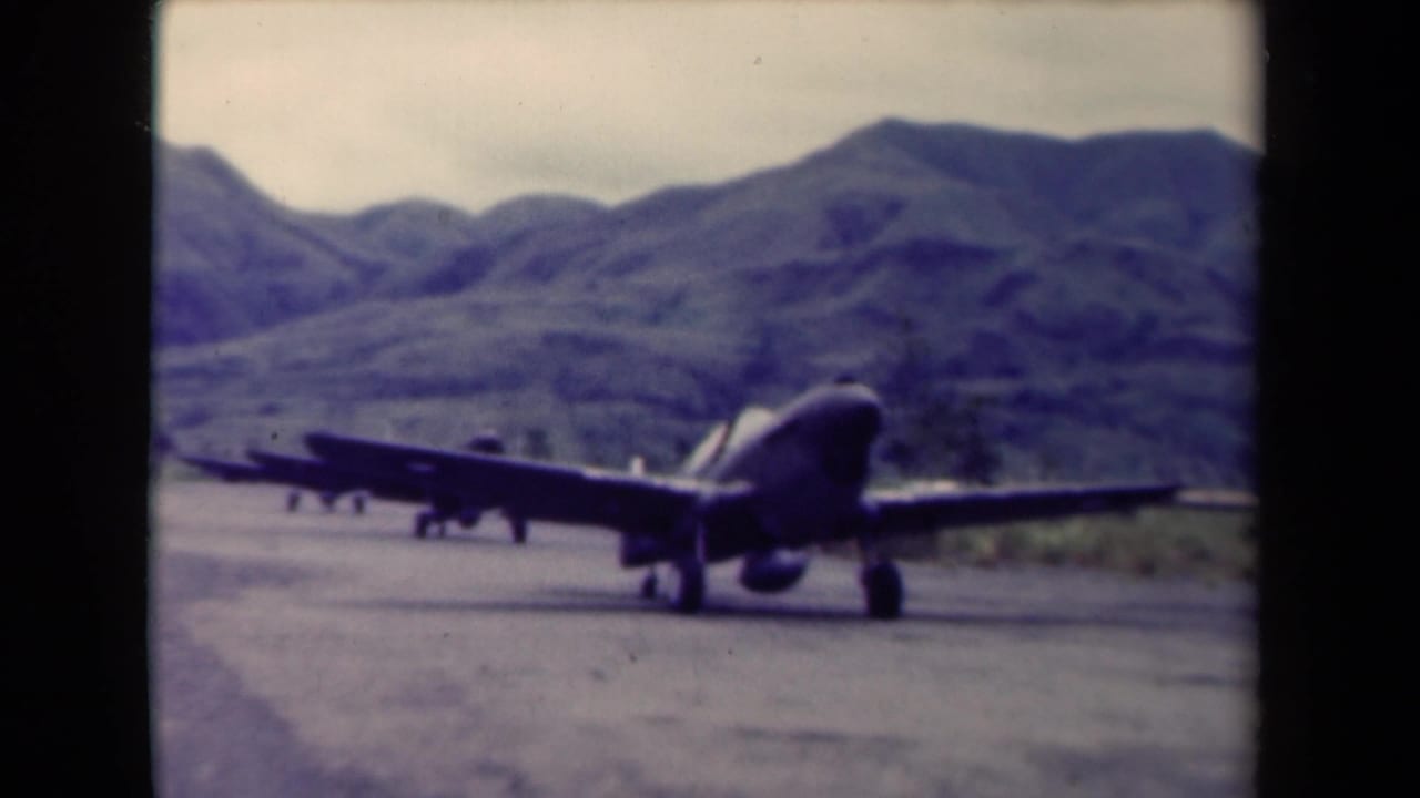 Military aircraft angled on a runway below mountain slopes.