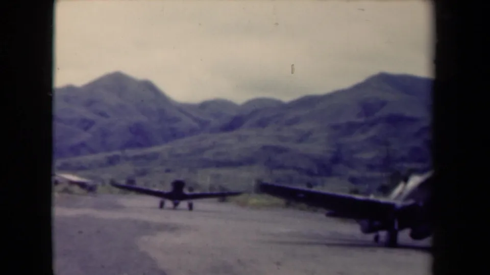 Final 1944 Papua New Guinea frame shows one aircraft partly entering the right edge and another on the airstrip ahead.