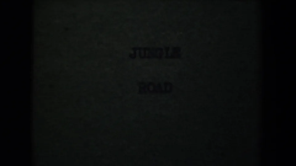 Dim 8mm title-card frame with the words JUNGLE ROAD faintly visible against a dark green background.