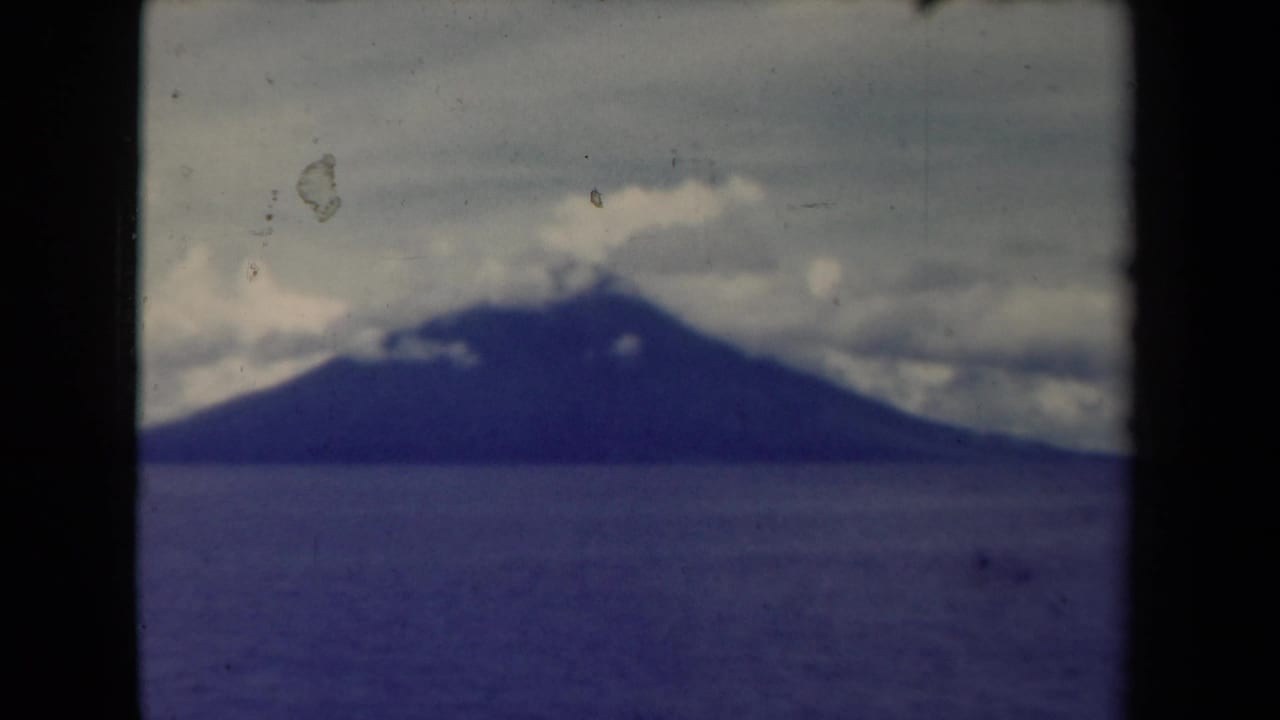 Distant mountain and broad water surface seen through aged film grain.