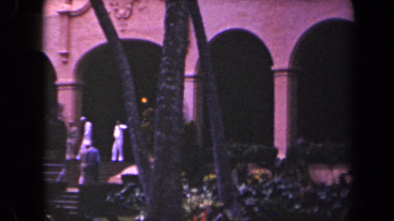 Two people in light clothing move across steps below large arches.