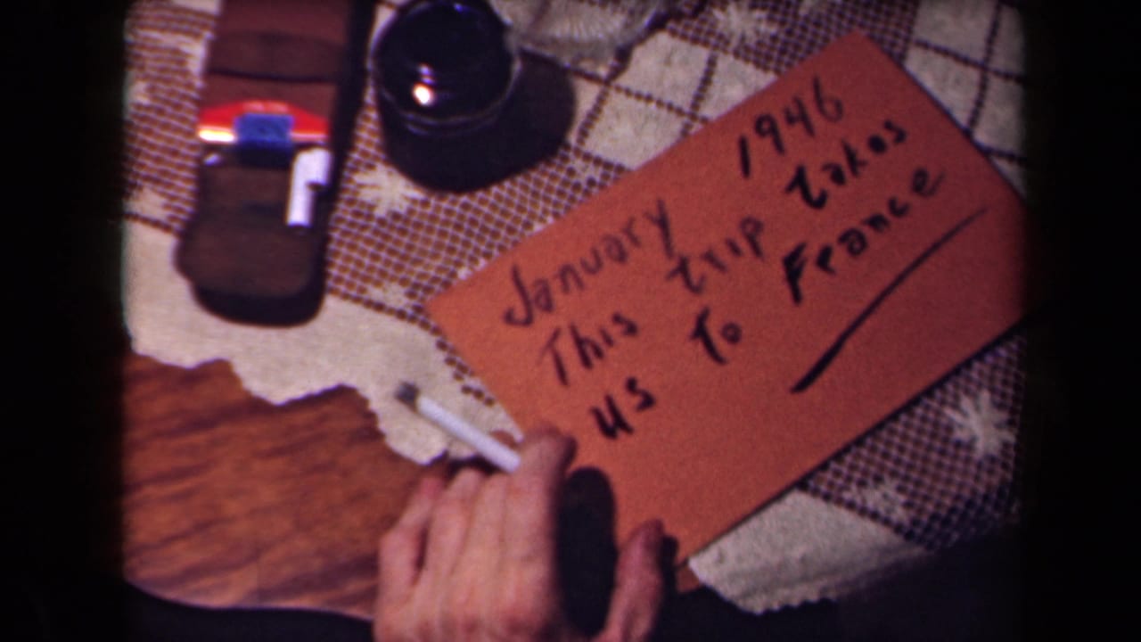 The completed handwritten card about a trip to France sits on a patterned tablecloth with an underline below the text.