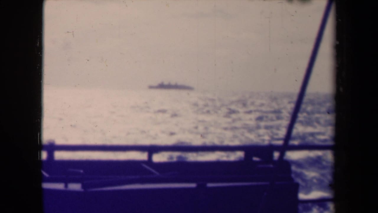 Distant ship on the horizon seen beyond a boat rail and diagonal support line.