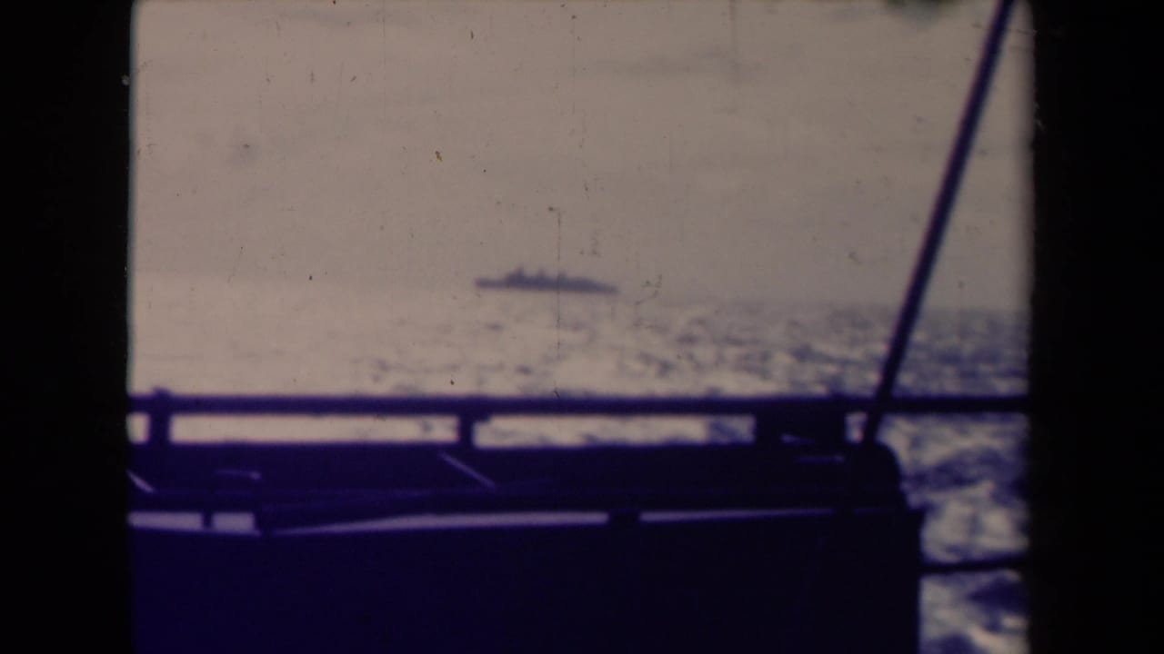 1945 France 8mm frame of a distant ship beyond boat railing, with rigging lines and dark frame edges visible.