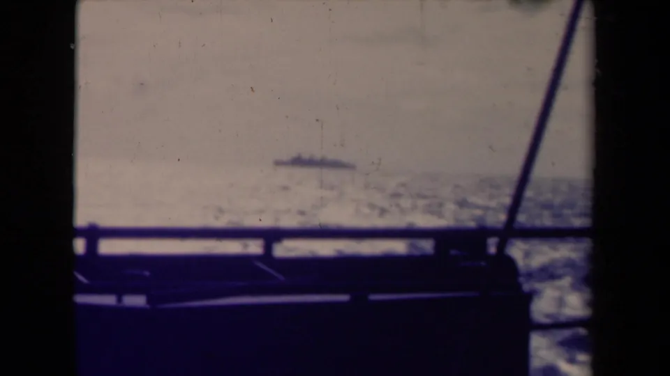 1945 France 8mm frame of a distant ship beyond boat railing, with rigging lines and dark frame edges visible.