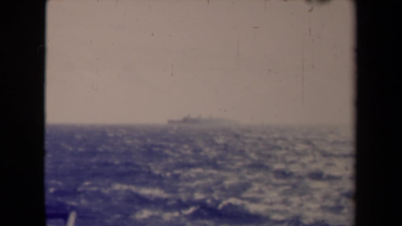 Soft 8mm frame from 1945 France showing choppy sea and a distant vessel barely above the horizon.