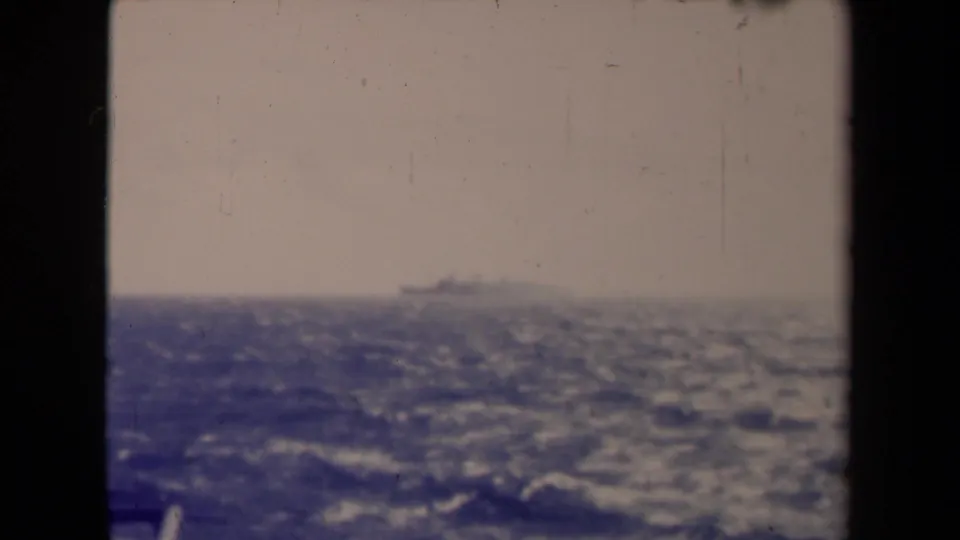 Soft 8mm frame from 1945 France showing choppy sea and a distant vessel barely above the horizon.