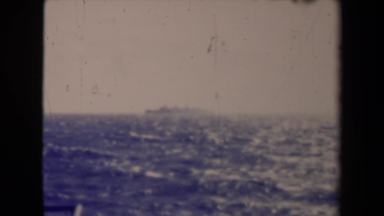 France 1945 8mm frame with a small distant ship, hazy sky, rough water, and visible film wear.