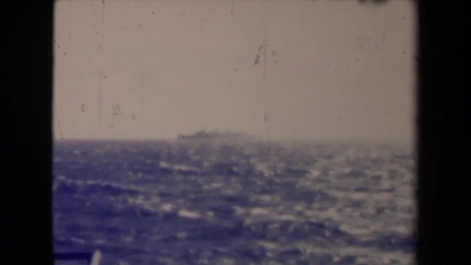 France 1945 8mm frame with a small distant ship, hazy sky, rough water, and visible film wear.