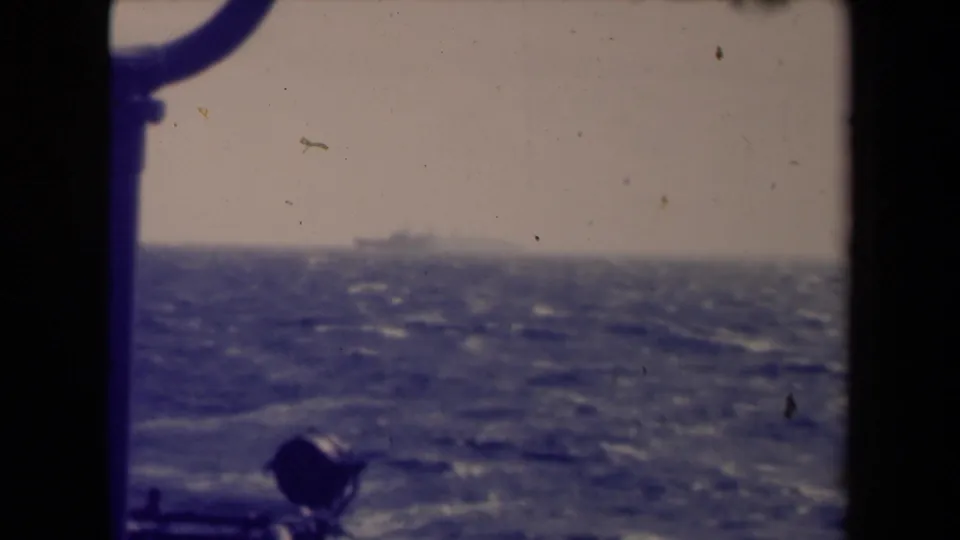 France 1945 8mm frame showing a distant ship over choppy water, with window hardware or rigging in the foreground.