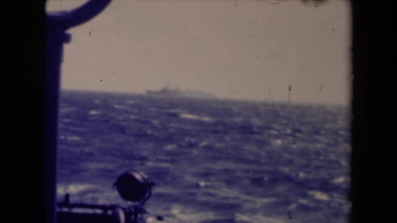Hazy ocean horizon with a distant ship and foreground ship fixture.