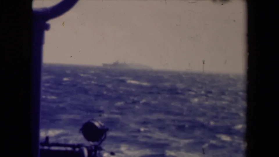Distant vessel crossing a hazy sea horizon, filmed from aboard a moving ship on 8mm footage dated 1945.