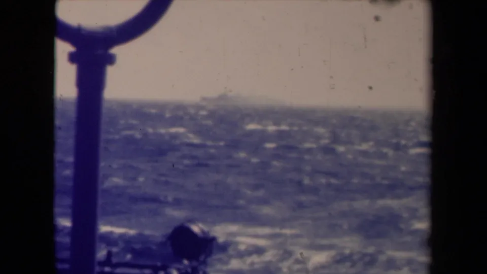 Final 1945 shipboard view of a distant vessel on the horizon, with choppy sea, hazy sky, and 8mm film marks.