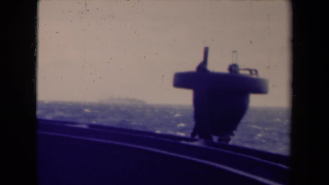 Dark ship structure in the foreground with open sea and hazy horizon beyond.