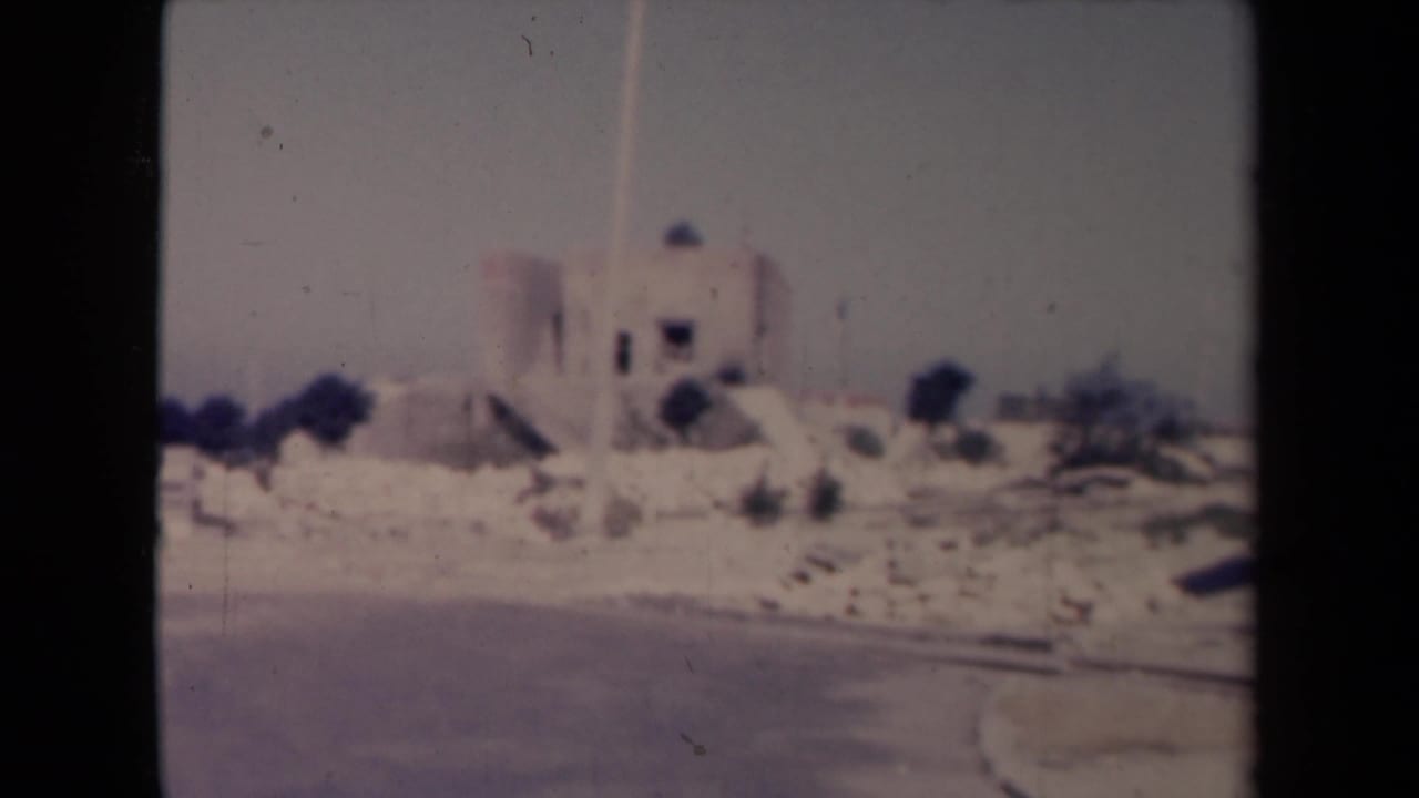 Pale building and roadside stones beside a curving road.