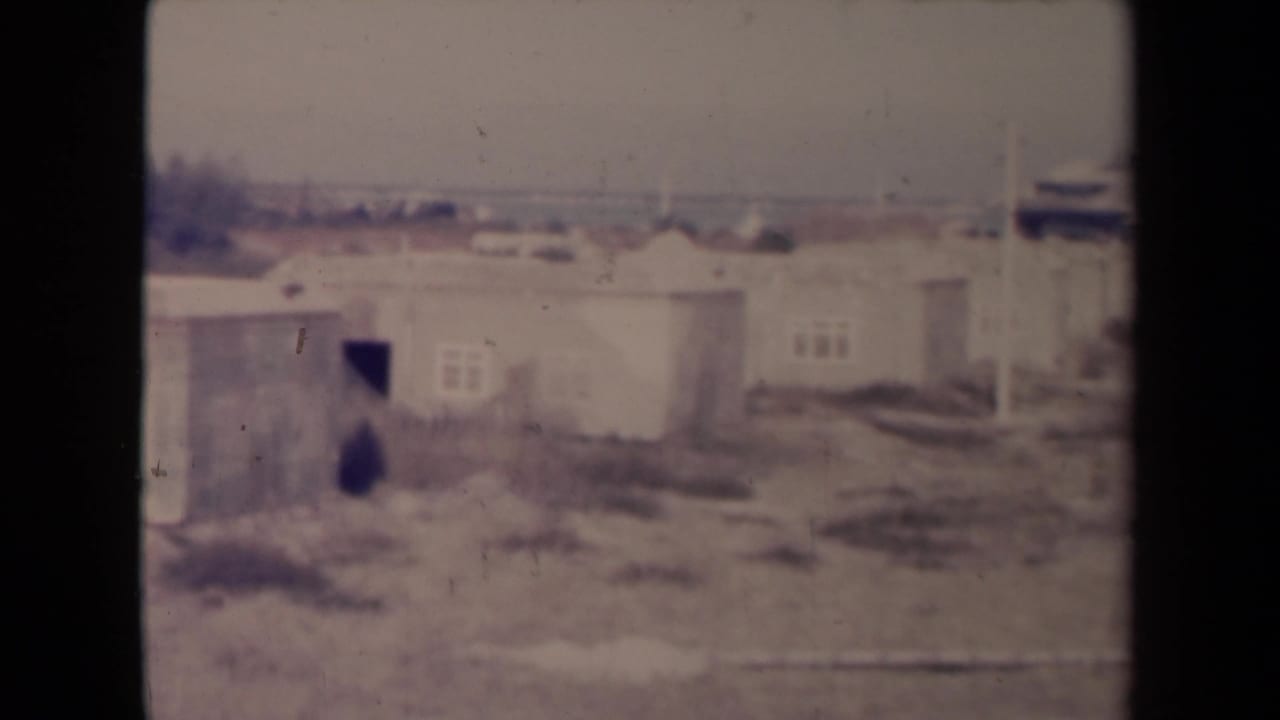 Soft 8mm view of low damaged housing across barren ground.