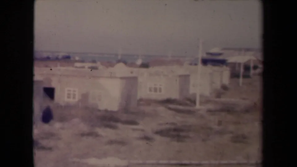 1945 France frame of worn housing units with dark openings and muted, grainy 8mm color.