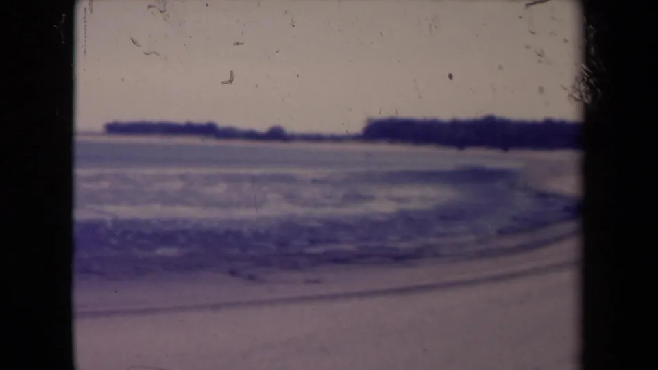 1945 France frame of a calm shoreline with water, distant land and visible 8mm frame edges.