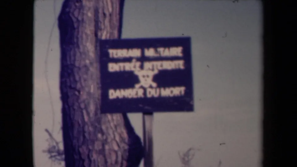 1945 France 8mm frame showing the military danger sign from a similar angle, with soft focus and visible film edges.
