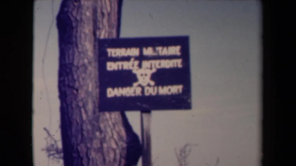 1945 France 8mm frame of the restricted military warning sign, with muted color, grain, and a dark vertical film edge.