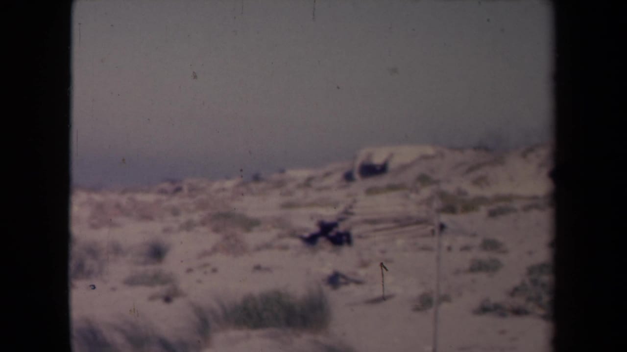 Sandy dunes with sparse beach grass under a hazy sky.