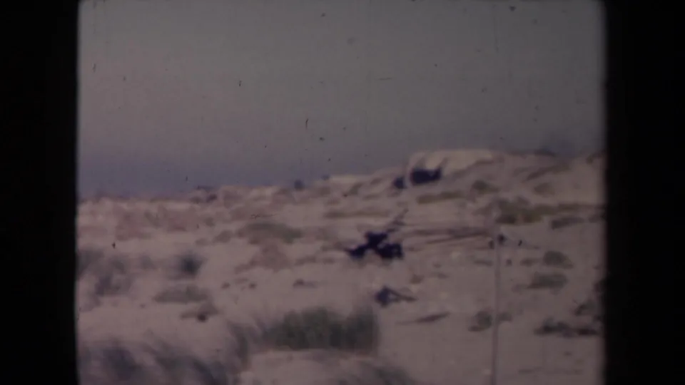 1945 France coastal frame with low dunes, scrub vegetation, pale sky, and 8mm gate borders visible.