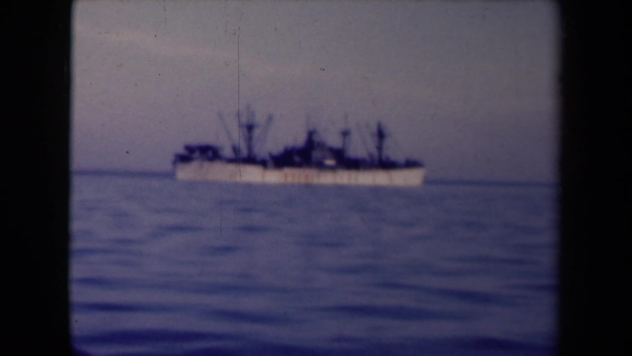 1945 France 8mm frame showing a distant large vessel on calm blue sea, silhouetted against a hazy horizon.