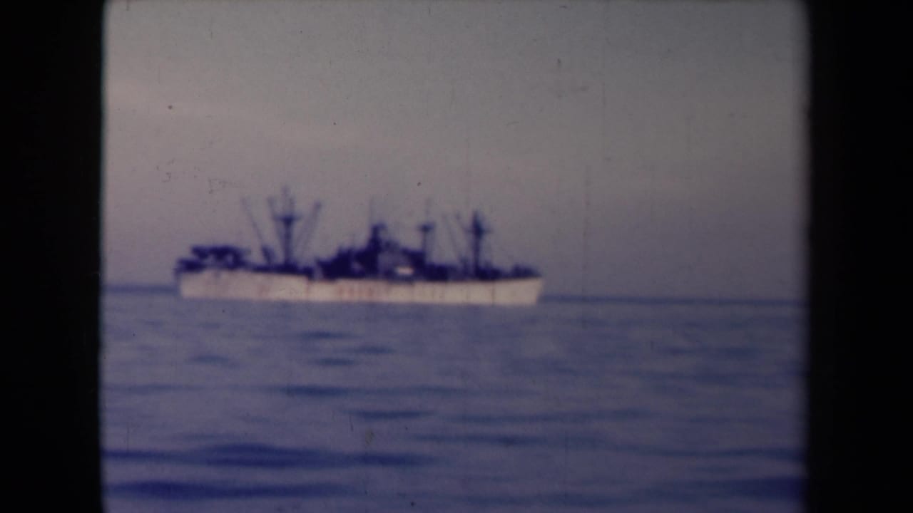 Distant large ship crossing calm water beneath a muted sky.