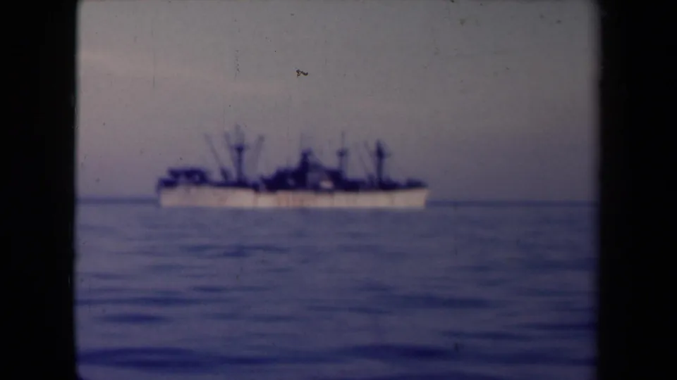 Distant 1940s France ship view on open water, framed by visible 8mm film edges and a pale sky.