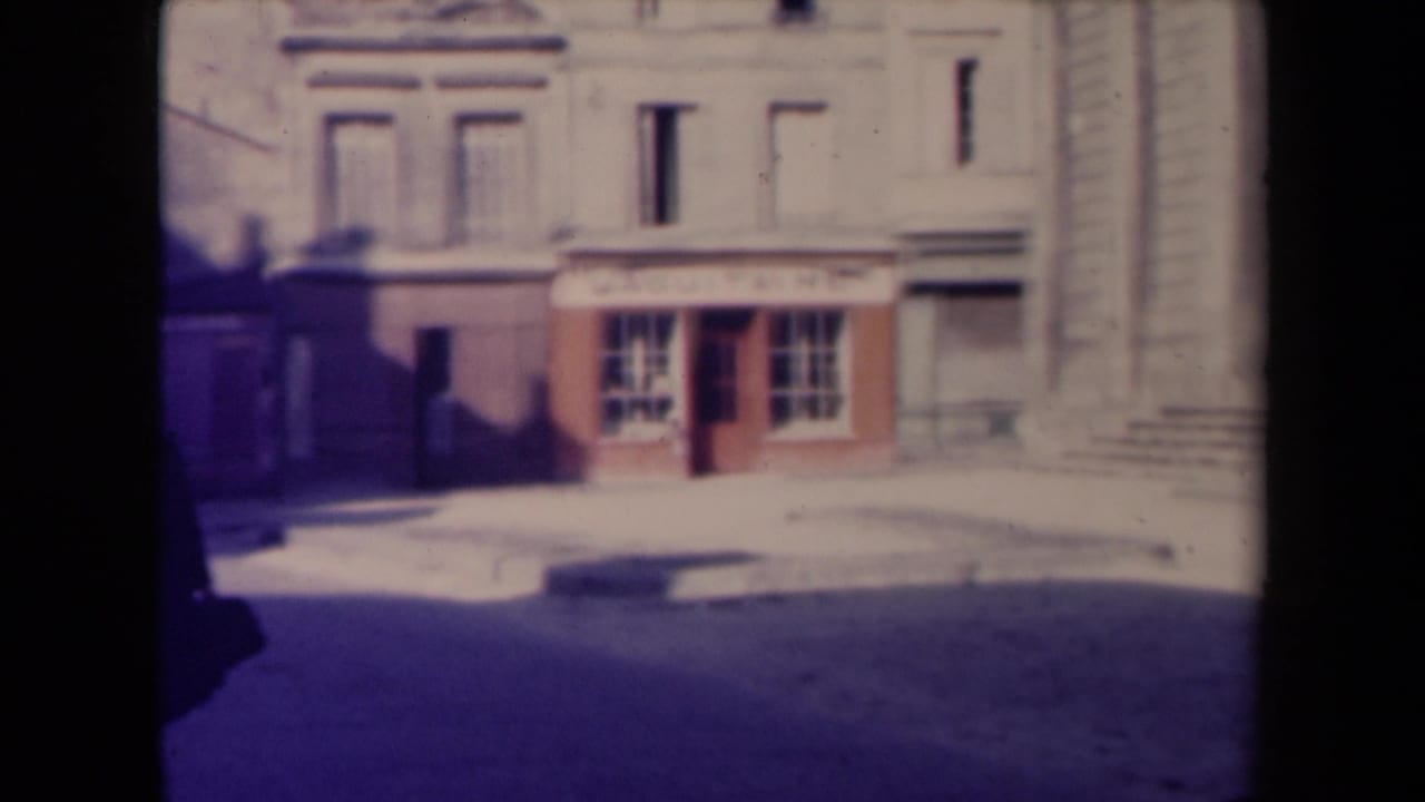 Shopfront with sign and pale building facade as the walking man moves partly out of frame.