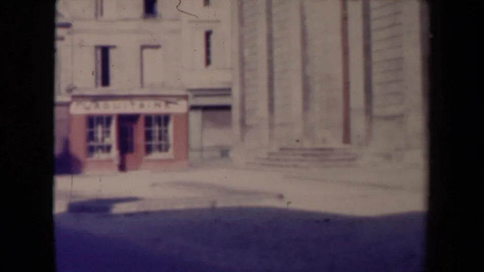The final frame shows the signed shopfront beside a large stone civic-style facade on a quiet French street in 1945.