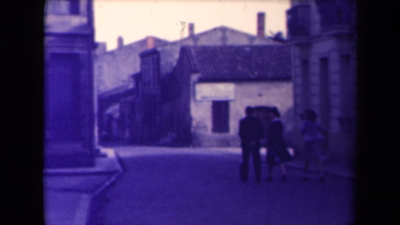 A small group of pedestrians continues away from the camera on a quiet street.