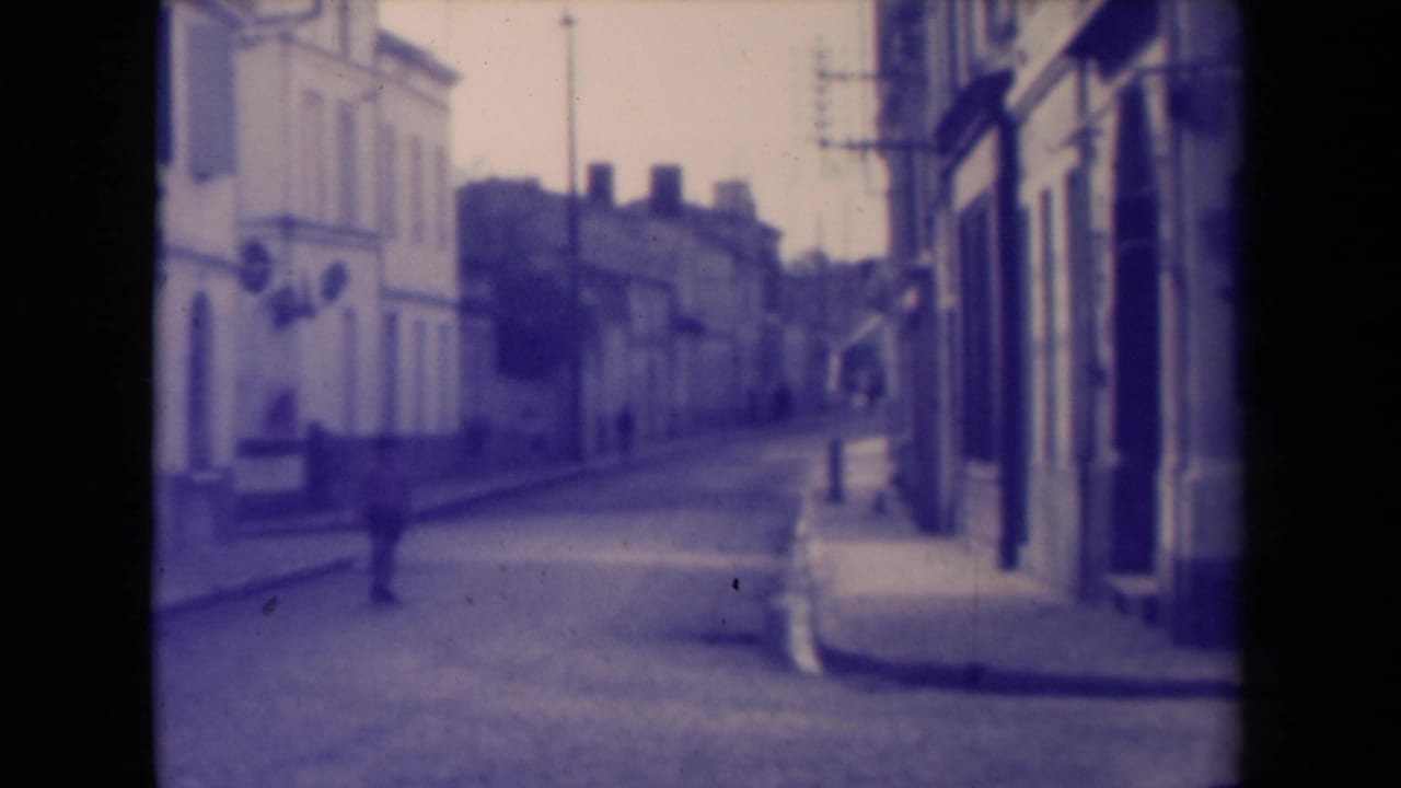 Quiet narrow street with storefront facades and a distant pedestrian.