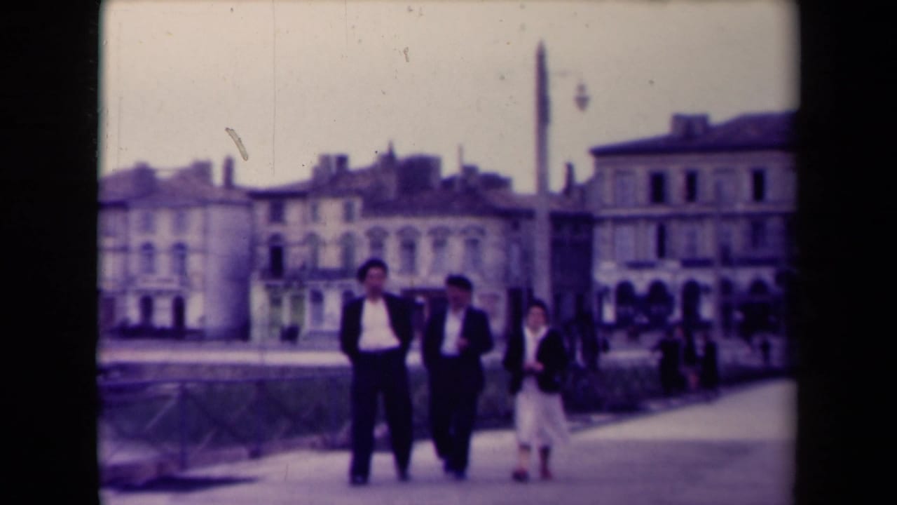 Near the end of the 1945 France clip, the group is closer to the camera, framed by a promenade, civic buildings, and a tall monument.