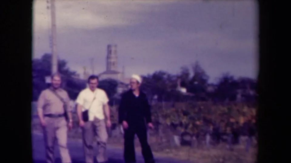 At the end of the clip, three men in civilian clothing and sailor-like dress walk close to the camera on a French rural road.
