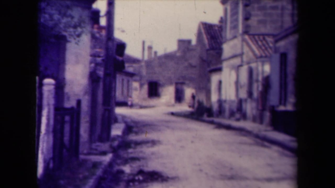Quiet narrow street lined with old buildings and a distant person near the center.