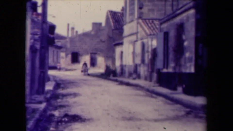 1945 France home-movie view of a quiet street, shuttered facades, and one person walking in the distance.