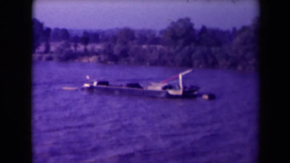 France 1945 8mm frame showing a low boat or partially submerged hull on purple-tinted water near a distant shoreline.