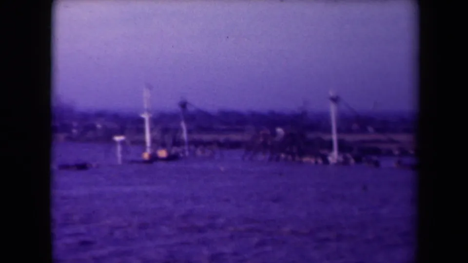 Purple-tinted 8mm frame of a French coastal scene with open water, distant shore, and possible navigation or pier structures.