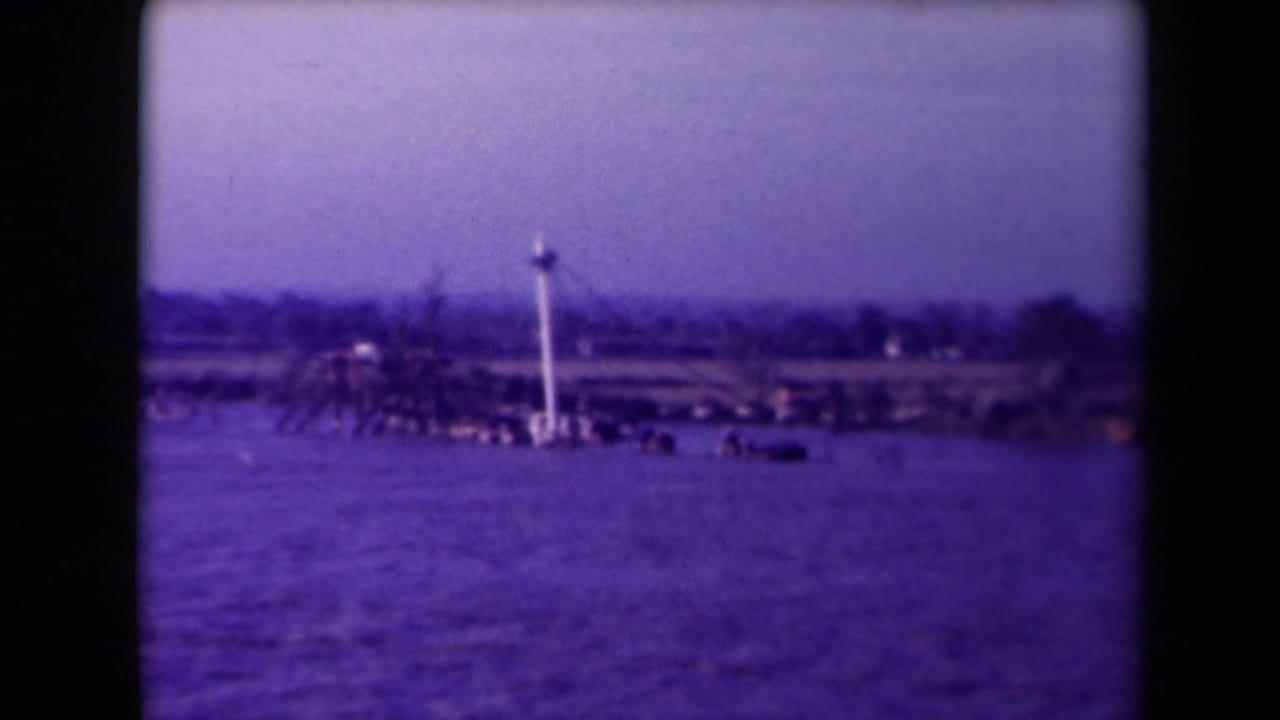 Distant bay view with a partially submerged boat and a tall mast near the shoreline.