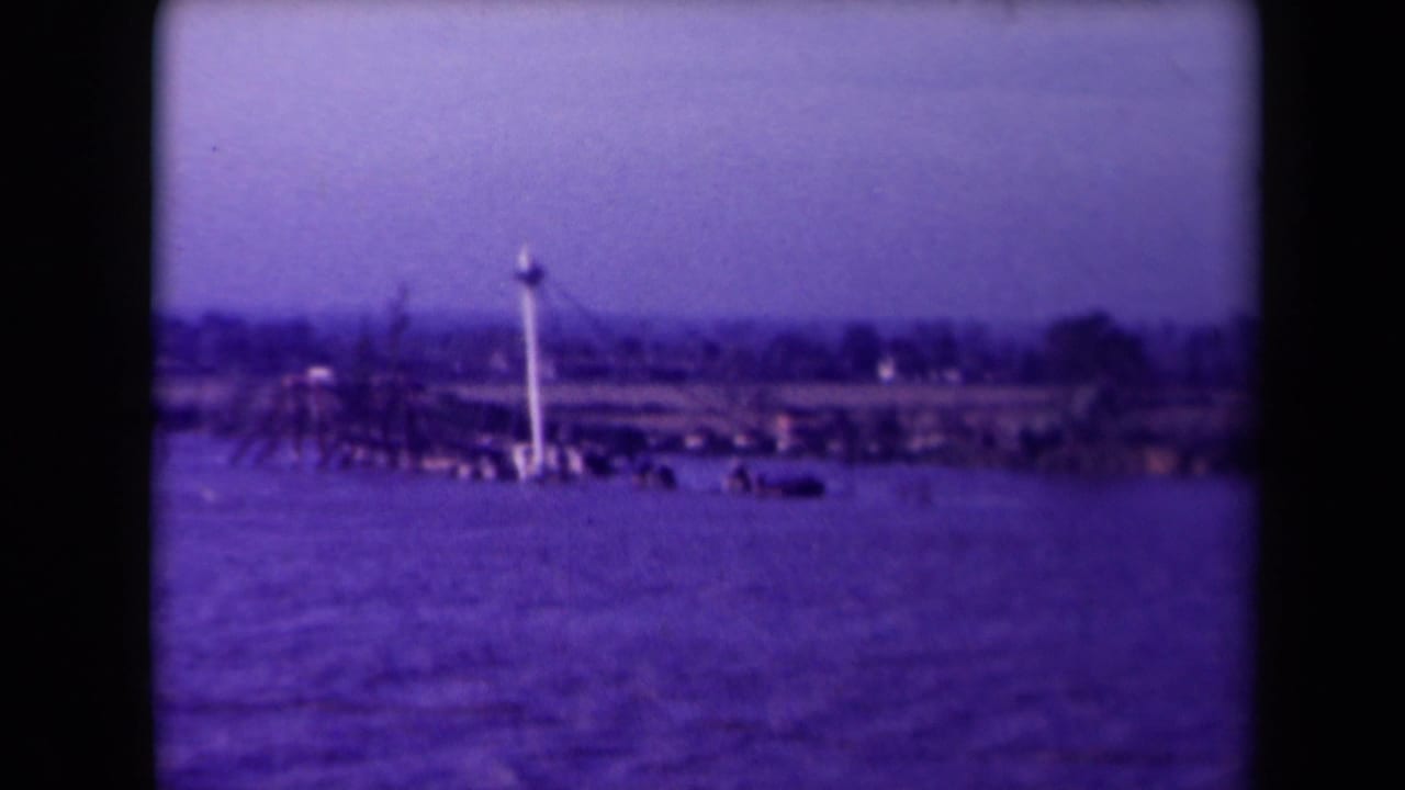 Wide water view with a damaged boat and mast near a flat shoreline.